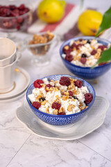Fototapeta na wymiar Blue bowl of cottage cheese with berries, honey and nuts for breakfast, selective focus.
