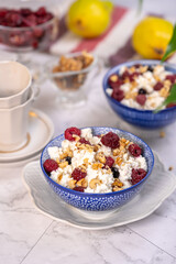 Blue bowl of cottage cheese with berries, honey and nuts for breakfast, selective focus.