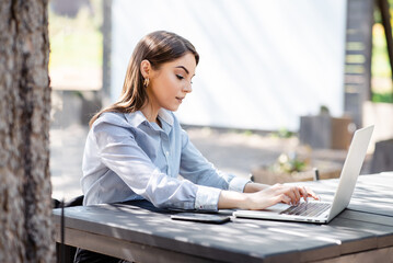 European businesswoman typing on laptop outdoors