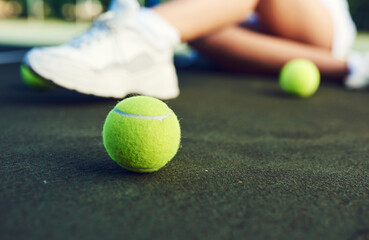 Grab a racket and ball and get playing. Closeup shot of a tennis ball on a tennis court with an unrecognisable woman sitting in the background.