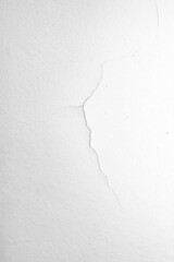 The white concrete wall is cracked, the paper is cracked