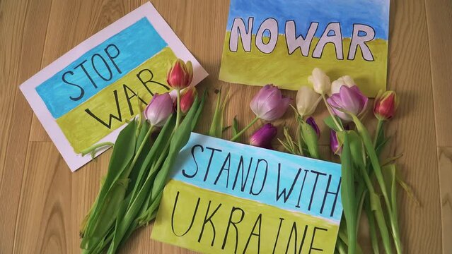 Three motivational packard with anti war texts against armored conflict in Ukraine with flowers on refugee center floor. Crisis, peace, stop aggression in whole world
