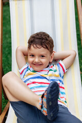 portrait of a happy boy in bright colored clothes. Summer. The boy lies on a chaise longue.