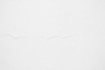 The white concrete wall is cracked, the paper is cracked