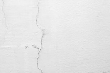 The white concrete wall is cracked, the paper is cracked