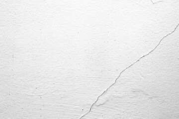 The white concrete wall is cracked, the paper is cracked