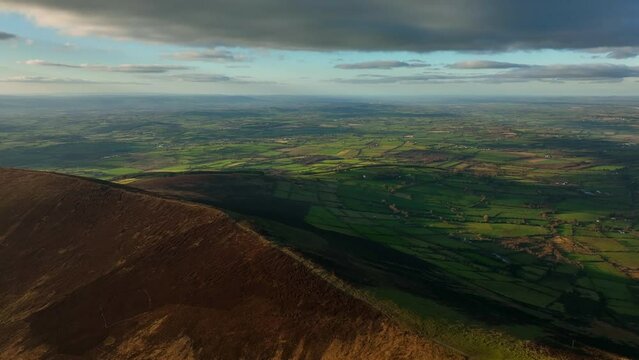 Mount Leinster, Carlow, Ireland, March 2022. Drone orbits Rathnageeragh hill facing west towards Garryhill with Corries Cross and Kilkenny in the distance at sunset.