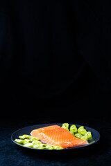 Salted fish salmon with pepper and onions on a black plate. Top view. Free space for your text.