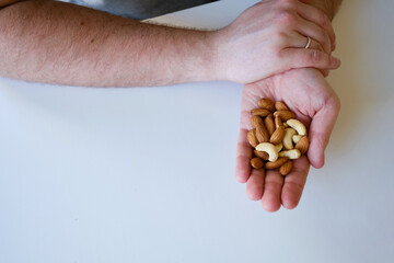 A man eats different nuts in the kitchen or at the work table. Healthy food. Healthy vegetarian...