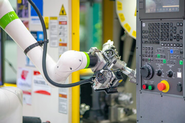 Factory 4.0 concept:  The collaboration of robot and CNC machine, automotive part is taken into CNC...