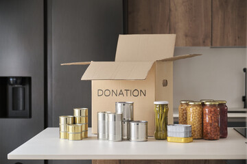 Fototapeta na wymiar Open donation box with food cans, legume jars and canned fish in kitchen. Help for people. Charity concept.