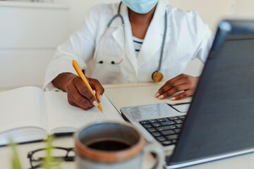 Unrecognizable doctor making notes at her desk. Doctor signing prescription for patient. Doctor advise patients at the doctor's office. Hand of an unrecognizable doctor writing a medical report.