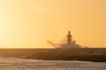Beautiful view of a breakwater with a lighthouse at sunset.