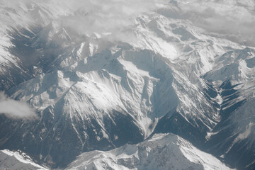 View from the plane. Mountains covered with snow. Clouds and mountains. Journey.