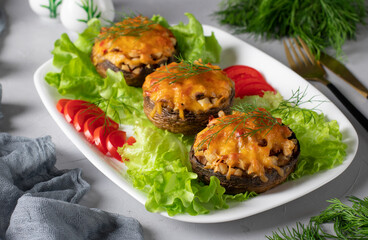 Baked champignons with turkey and cheese, hot festive appetizer on white plate