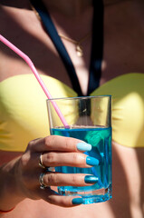 blue lagoon cocktail. hand with blue manicure. summer vacation