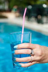 blue lagoon cocktail. hand with blue manicure. summer vacation and pool party