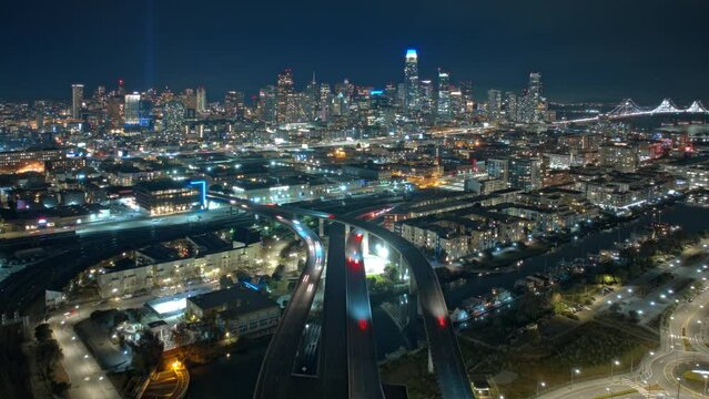 Scenic night city view on San Francisco downtown with cinematic highway. Drone flight over urban junction overpass at night. Rush hour traffic city panorama San Francisco business district aerial 4K