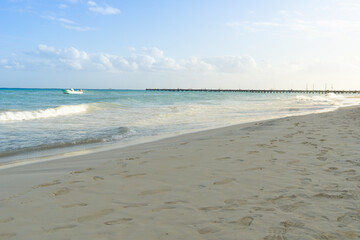 View of the sea, beach and sky. The deserted beach is covered with traces of people. Early morning on the seashore, the pier is visible in the distance.