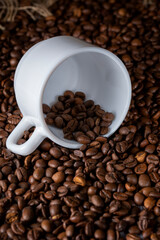 
Roasted coffee beans and white ceramic cup on the table
