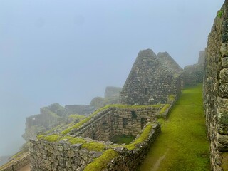 the wall from ruins of the ancient city of machu picchu with clouds over the mountain	