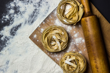 Pasta nests on flour on a black background. Shape of pasta. traditional cooking