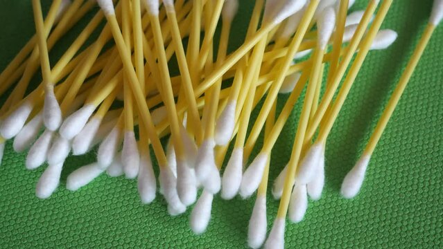 Cotton buds lie on a rotating green surface. Cotton swabs close-up.
