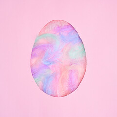 Egg shape frame with natural colorful feathers on pastel pink background. Flat lay creative Easter concept