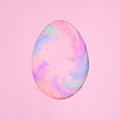 Easter creative concept. Egg shape with natural colorful feathers on pastel pink background. Flat lay