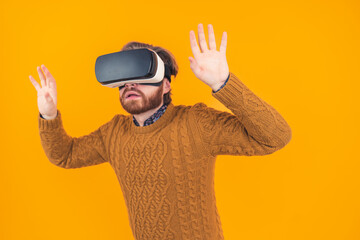 young caucasian man using vr googgles while having his hands raised up in the air. High quality photo