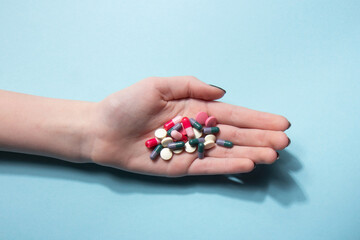 Tablets in the palm of your hand. Vitamin tablets and capsules on a blue background. Dietary supplements