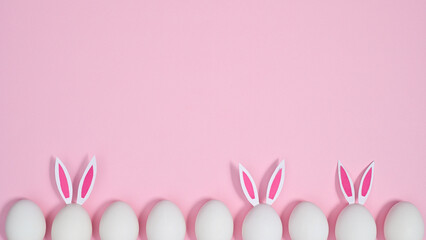 Obraz na płótnie Canvas Creative Easter copy space background with eggs with bunny ears on pastel pink theme. Flat lay