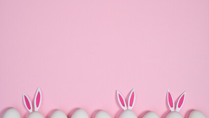Creative Easter copy space background with eggs with bunny ears on pastel pink theme. Flat lay