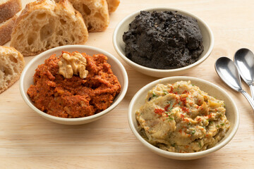 Bowls with fresh home made Baba ganoush, Muhammara and black Hummus close up for appetizer 