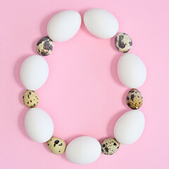 Creative copy space egg shape frame with white and quail natural eggs on pastel pink background. FLat lay
