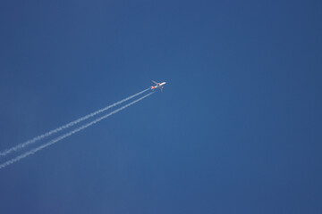 a passenger plane flies in the blue cloudless sky and has condensation trails behind it