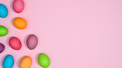 Vibrant pastel pink background with copy space and colorful Easter eggs. Flat lay creative minimal concept.