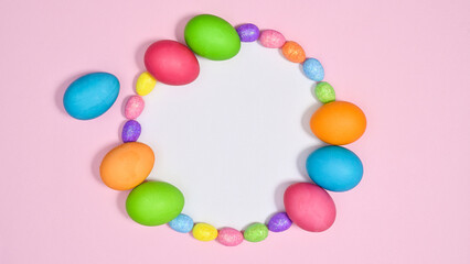 Paper card copy space on pastel pink background with colorful natural Easter eggs frame . Flat lay concept