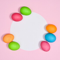 Paper card copy space on pastel pink background with colorful natural Easter eggs. Flat lay concept