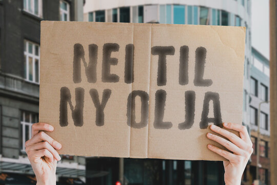The phrase " Nei til ny olja " on a banner in men's hands with blurred background. Fossil. Pollution. Process. Heavy. Logistics. Stock. Trade. Pumping. Barrel. Nature. Hydraulic. Damaged