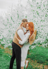 Romance, people, love and dating concept - happy couple over cherry blossoms background. Spring