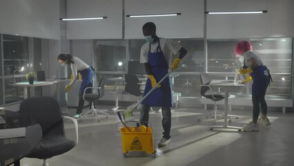 Diverse team of janitors in facemask clean empty office and leave - Powered by Adobe