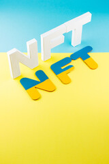 NFT inscription with white 3d letters on a blue-yellow background. Non-fungible token against background of colors of the Ukrainian flag. Crypto art concept