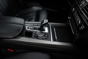 Gear lever for automatic transmission. Transmission control dial. Premium luxury SUV elements. Car air conditioning and climate control. Black interior of a modern business class car.