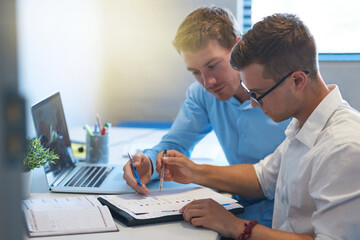Working hard is the easiest method for achieving success. Shot of two handsome young businessmen working together in their office.