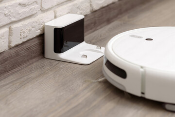Robot vacuum cleaner cleaning the house. Device returns to the charging station after cleaning the...