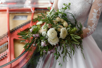 Wedding rustic bouquet in the hands of the bride. A beautiful luxurious bouquet consisting of ranunculus and cream-colored roses. Wedding day. Creation of a family, marriage ceremony of a couple.