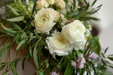 Wedding rustic bouquet in close-up. A beautiful luxurious bouquet consisting of ranunculus and cream-colored roses. Wedding day. Creation of a family, marriage ceremony of a couple.