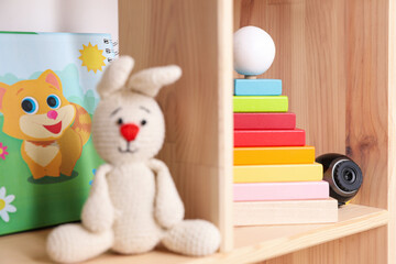 Small camera hidden among toys on wooden shelf in baby room