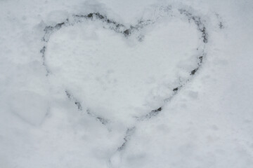 A heart drawn on a background covered with first snow. 